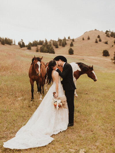 bride and groom kissing by horses