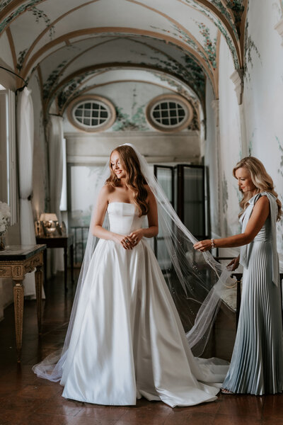 Mother helping Bride with her  beautiful long veil on her wedding day in a castle Southern California
