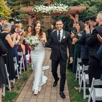 Bride and groom walking down the aisle during outdoor ceremony | Summer Wedding at Minerals Hotel | Vernon Township, New Jersey