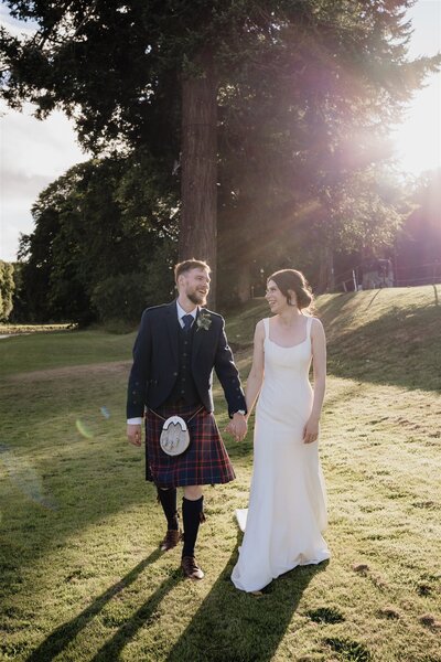 A close photography of a couple as they walk hand in hand down the aisle after their outdoors Glen Tanar wedding ceremony.