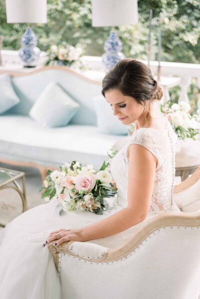 Bride holding rose bouquet and sitting on old fashioned sofa