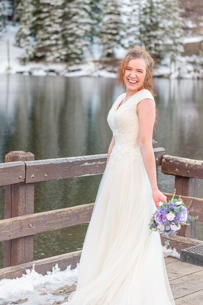 A bride stands on a bridge in the snow