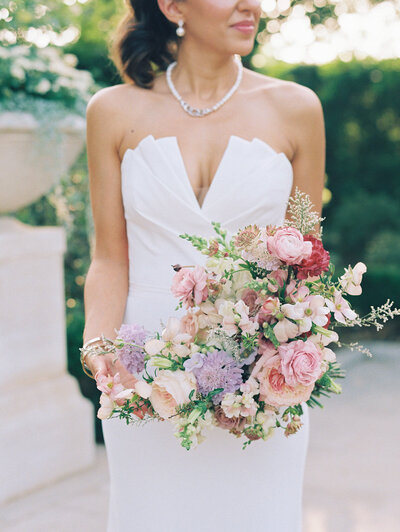 Bride holding a colorful bouquet in front of her white dress