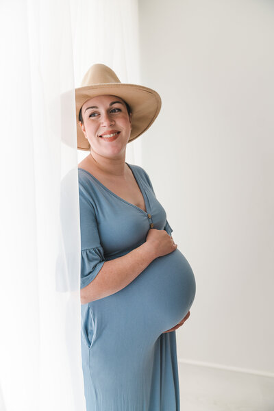 Pregnant woman smiling wearing hat