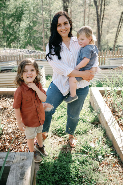 woman standing in her garden with her two children