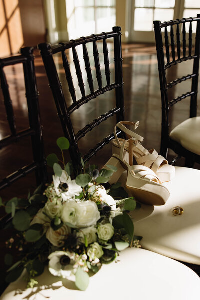 Bridal floral, shoes, and wedding rings on the chair for details at the ceremony space. 