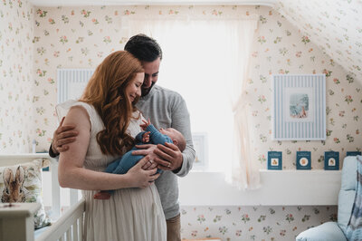 Couple holding their newborn in a softly lit nursery, captured in a natural light family photography session