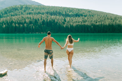 man and woman walking into lake