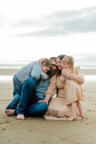 Family cuddled together and smiling during a playful photo shoot on Pismo Beach