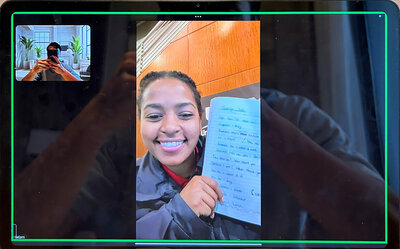 Smiling student on a virtual Japanese coaching call proudly showing her handwritten Japanese practice sheet