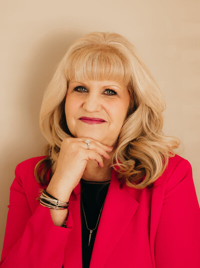 Jessica wearing a white blazer, smiling as she writes in her planner