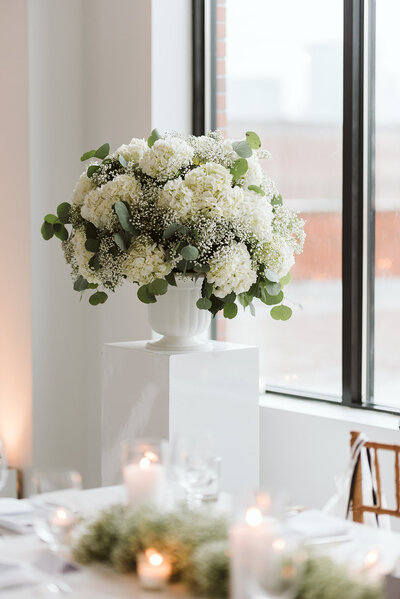Hydrangea and baby’s breath flowers in a vase on a pedestal