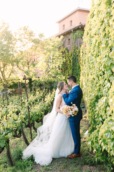 bride and groom embracing in lush green napa vineyard.