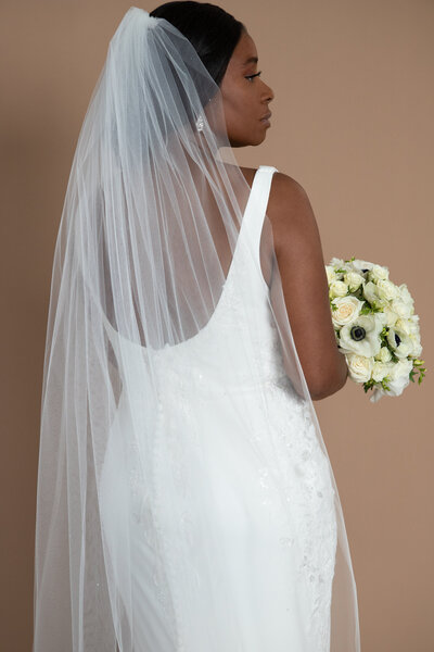Bride wearing a floor length veil with scattered crystals and holding a white bouquet