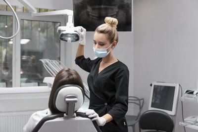 A female dentist adjusting the light while working on a patient.