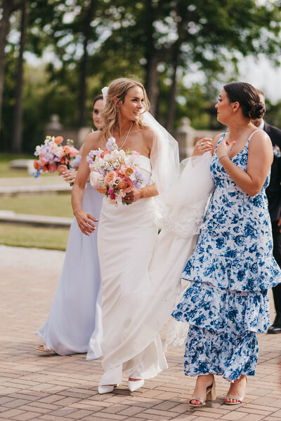 bride and bridesmaids walk holding pastel bouquets
