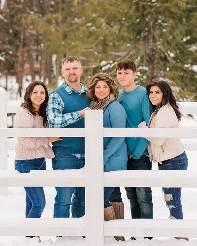 Family standing close and smiling on a white bridge at an outdoor family portrait location in North East, PA.