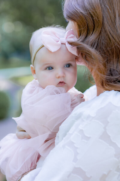 baby girl in pink up close on mom snuggled in outside natural light family time