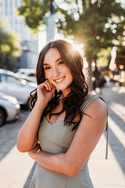 Best Salem Senior Photographer, young girl standing on a downtown sidewalk with sun flare behind her