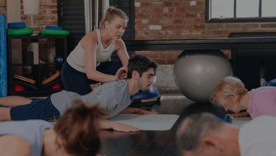 woman giving hands-on assistance in a mat pilates class 