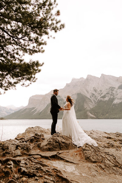 Bride and groom holding hands in front of Moraine lake and the mountains of Banff National Park Canada
