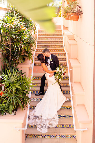 Bride and Groom standing on staircase with long dress at La Valencia wedding venue
