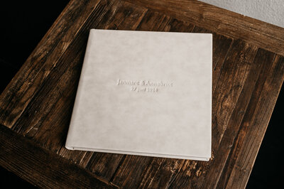 Een beige trouwalbum op een bruin tafeltje.