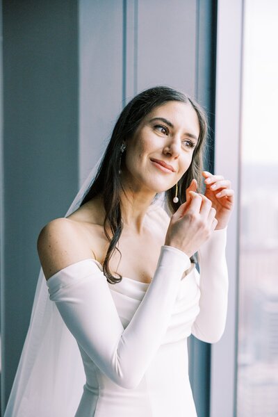Bride putting earrings on