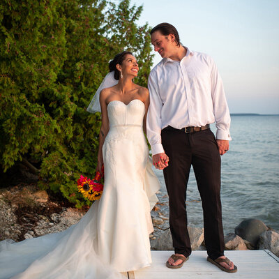 bride and groom hold hands in front of lake and trees
