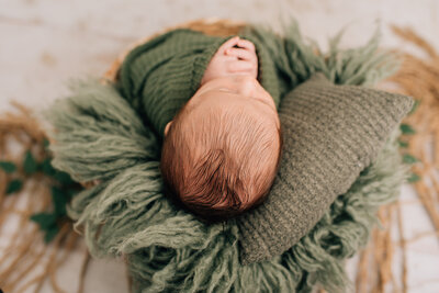 A close-up of a newborn baby boy, wrapped in white at his newborn session with Sharon Leger Photography.