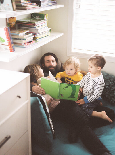 dad reading books to three kids in charlotte home