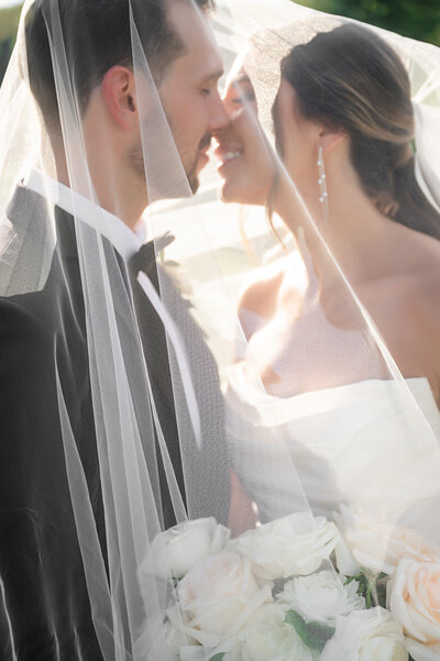 bride and groom under veil in romantic candid wedding photo