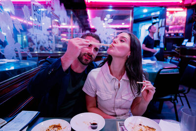 man feeds woman with chopsticks