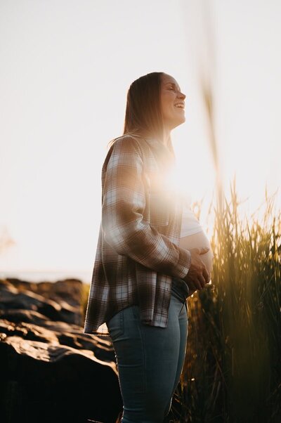 Gravid kvinna håller upp sin klänning över sin gravida mage.
