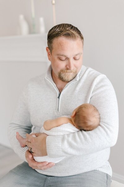 A father holds his newborn baby during a newborn photo session in NJ