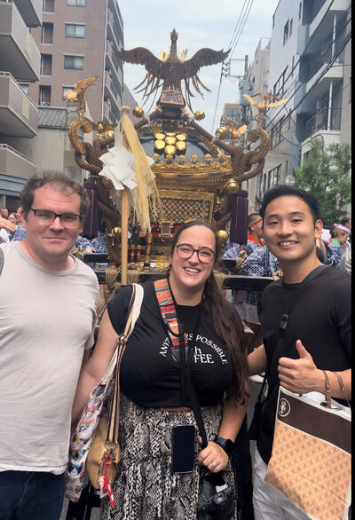 Yasushi and two guests smiling in front of a traditional Japanese mikoshi during a Japan Blend private Tokyo tour
