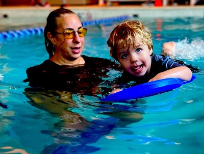 Swim coach patiently guides a little boy in learning how to swim.