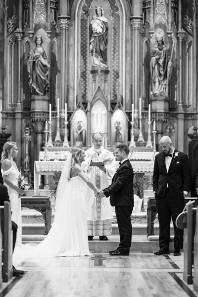 A bride and groom hold hands and exchange vows inside of St Mary Catholic Church in German Village