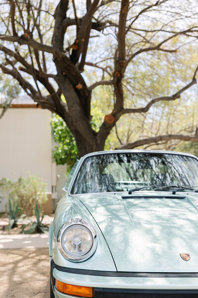 A stylish wedding detail shot at the Arizona Biltmore featuring pearl-embellished bridal sandals and an elegant hand fan resting against the venue’s iconic art deco architecture, bathed in warm desert sunlight.