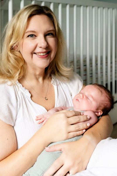 Swaddled baby on mother's lap while she is touching his arms