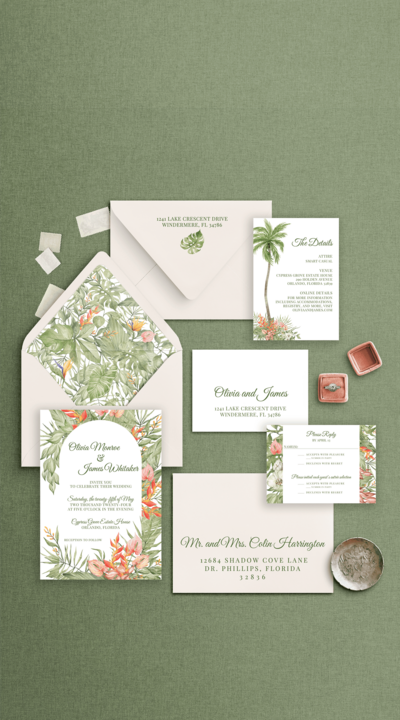 Flat lay of a tropical-themed wedding invitation suite