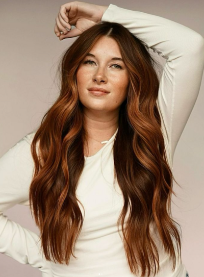 Woman with vibrant red balayage waves styled by Salon Beau, highlighting a natural, low-maintenance look.