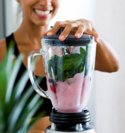 Woman smiling while making a smoothie in a blender