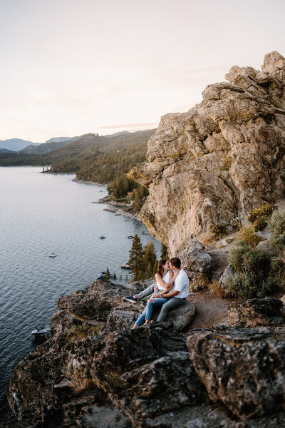 Romantic engagement photo with couple overlooking Tahoe from a cliff.