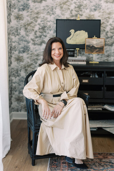 Interior designer in Lake Norman, NC, standing in a stylish hallway with modern gold-accented wall decor.