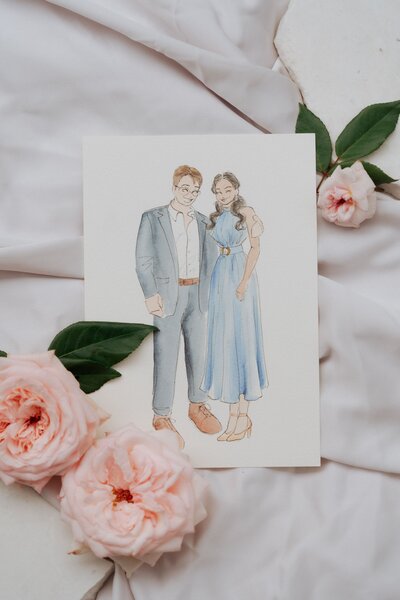 A watercolor portrait of a couple, with the man in a suit and the woman in a blue dress, standing together.