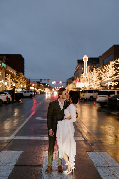A newlywed couple standing in the middle of the street kissing 