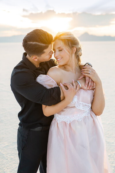 A couple embracing on the Utah Salt Flats at sunset with golden glow