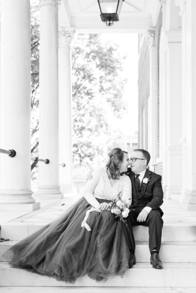 couple sitting on marble steps on wedding day