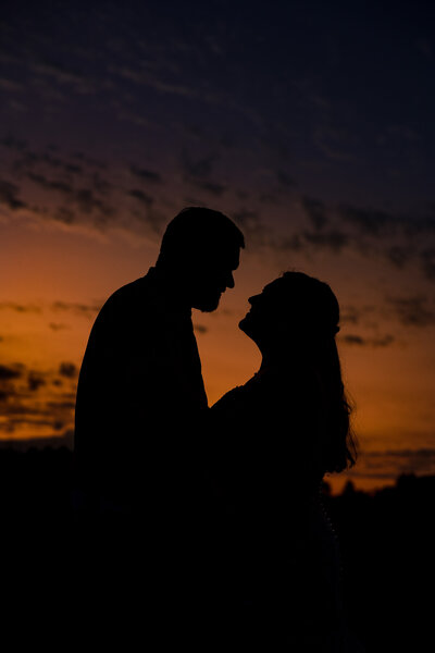 Bride and groom backlit by sunset